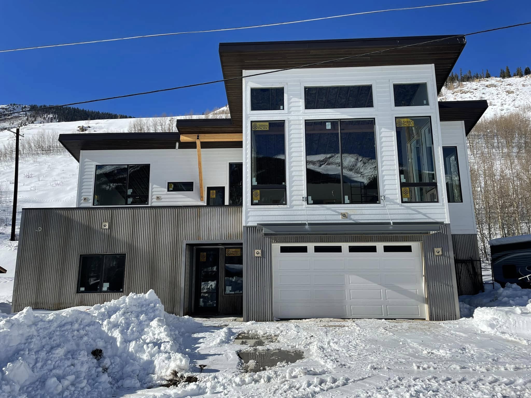 Mostly completed contemporary white and charcoal home in a snowy mountain setting